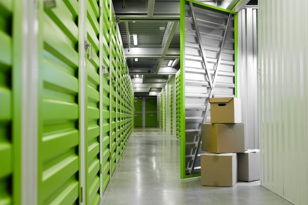 surface-image-green-self-storage-facility-with-opened-unit-door-cardboard-boxes-copy-space